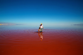 مردی به همراه فرزندش در آب دریاچه راه می‌روند. 