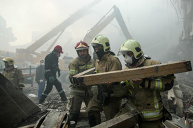 تیم های امداد و نجات و گروه های آتش نشان در حال قطعه قطعه کردن آهن آلات به جا مانده از ساختمان هستند.