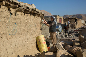 پیرمردی از اهالی روستای کوییک حسن در حال بازسازی دیوار خانه خود است که در زلزله اخیر خراب شده است.