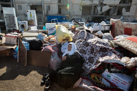 پیرزنی در میان اثاثیه جمع آوری شده از خانه‌های تخریب شده در  زلزله سرپل ذهاب نشسته است.