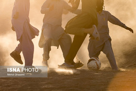کودکان روستای تپه‌کنیز در استان سیستان و بلوچستان، برای تصاحب توپ فوتبالشان تکاپو می‌کنند. روستای محروم تپه‌کنیز، چسبیده به دیوار مرزی بین ایران و افغانستان است. برخی خیرین هر از گاهی اقلام و کمک‌هایی را برای ساکنان این روستا می‌برند. این توپ فوتبال، یکی از کمک‌های همین خیرین است. شاید بازی فوتبال در میان زمین‌های خاکی، تنها تفریح این کودکان باشد؛ تفریحی که می‌تواند آنها را برای دقایقی از دنیای پر از مشکلاتشان فراری دهد.