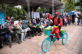 یک سیاه، درپانزدهمین جشن خانه تئاتر، سوار بر دوچرخه در اطراف محوطه نمایش، به سرگرم کردن مردم میپردازد 