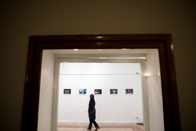 یک زن در حال تماشای عکس‌های گالری مرتبط با پانزدهمین جشن خانه تئاتر