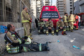 نیروهای آتش نشان در حال استراحت بعد از مهار آتش‌سوزی مجتمع مسکونی «پارامیس»