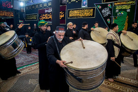 ابوعبدالزهرا به کمک یکی از جوانان موکب عزاء نجف اشرف طبل ویژه خود را بر گردن می اندازد و آماده شروع مراسم عزاداری می‌شود.
