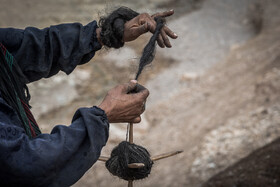 یکی از زنان روستای «پِز» سفلی در حال ریسمان بافی با پشم بُز 
