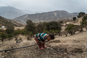 کودکی از اهالی روستای «پِز» در حال آب خوردن از شيلنگي كه در طبيعت رها شده است. این شلنگ دور ریز آب‌های گرفته شده از چشمه است. 

