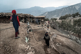 مادر و دختر روستایی بر روی پشت بام و حیاط خانه، در حال آماده کردن آغل گوسفندان. نزدیک غروب مردها گوسفندان را به خانه بر میگردانند و زنان جهت دوشیدن شیر و تمیز کردن آغل آماده می‌شوند.