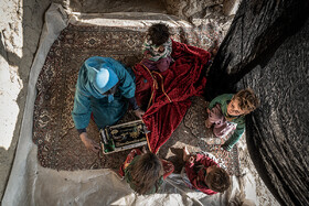 یکی از زنان جوان روستای سربیشه به همراه کودکان خردسال خود و همسایه در حال دوخت لباس محلی در ایوان منزل خود. 
