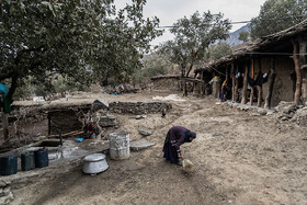 زنی از اهالی روستای سربیشه در حال جارو کردن حیاط خانه خود
