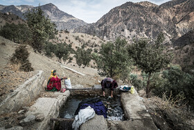 مادر و دختری از روستای هیرمان در حال شستشوی لباس‌های خود در حوضچه مصنوعی پر شده از آب چشمه
