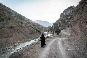 خدیجه کاظمی بانوی ۶۲ ساله روستای هیرمان در جاده در انتظار وسیله‌ی نقلیه، زنان برخی روستاهای دوردست یک روز از هفته را برای خرید مایحتاج زندگی به مرکز بخش می روند که در راه برای تهیه وسیله نقلیه با مشکلات فراوانی مواجهند. 
