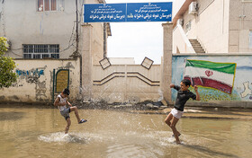 بچه ها مشغول آب بازی در سیلاب هستند.