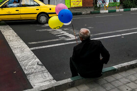 آبان ماه ۹۸ - تهران - خیابان بهار - پیرمرد فروشنده دوره‌گرد در حال فروش بادبادک‌های رنگی