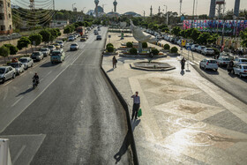 خیابان سجاد اصفهان - مردی در انتظار رسیدن اتوبوس در بعداز ظهر یک روز تابستانی آب می نوشد .