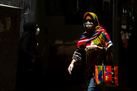 زنی نگران از  افزایش کرونا در گرمای ظهر تابستانی در حال عبور از پیاده رو میدان آزادی کرمان است.