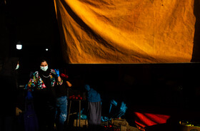 زنی بعد از  خرید روزانه در بازار میوه فروشان کرمان درتابش نور عصرگاهی تابستان کویر از زیر سایه بان عبور می کند.