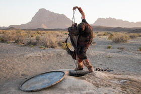 یک کودک در دهستان کوه سفید خاش در حال بیرون کشیدن آب از چاه، اهالی این دهستان برای دریافت آب آشامیدنی از چاه باید مسافت زیادی را طی کنند.