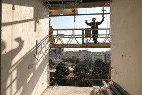 یک کارگر در حال اندازه‌گیری محل اتصال قطعات نمای ساختمان