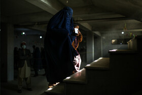 راضیه بگم بهمراه فرزندش پس از دریافت سبد غذایی از طرف سازمان جهانی غذا در حال خارج شدن از دفتر تحویل اقلام دریافتی است.