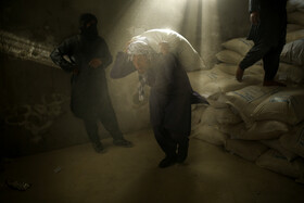 کارگران بخش تحویل سبد غذایی خانوارهای تحت پوشش سازمان جهانی غذا در حال آماده سازی اقلام غذایی هستند.