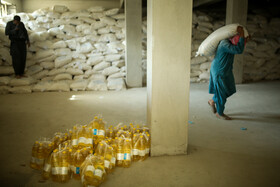 کارگران بخش تحویل سبد غذایی خانوارهای تحت پوشش سازمان جهانی غذا در حال آماده سازی اقلام غذایی هستند.