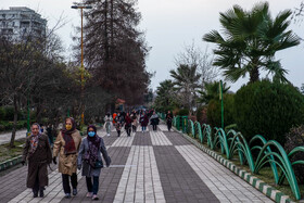 مردم در اطراف استخر لاهیجان در حال پیاده‌روی هستند.