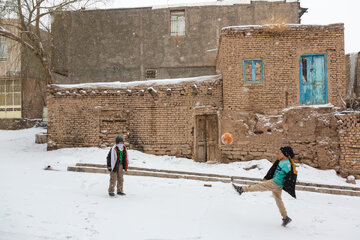 کودکان در یکی از کوچه‌های برفی روستای برزنون در فصل زمستان مشغول بازی هستند.