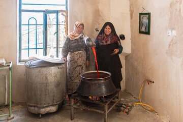 دو زن در حال تهیه رب گوجه‌فرنگی در فضای داخلی یکی از خانه‌های روستای برزنون در فصل تابستان.