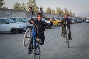 تعدادی از کودکان و نوجوانان در حاشیه جاده نصرت‌آباد، اقدام به انجام حرکات نمایشی با دوچرخه‌هایشان می‌کنند