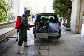 پرسنل آرامستان در ورودی سالن تطهیر در حال ضدعفونی کاور  یک بیمار کرونایی است. پس از هر مراجعه ماشین، کاور حمل، چرخ، جعبه حمل جسد کامل ضدعفونی میشود.