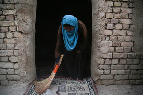 گل‌مهره، دختر جوان این خانواده افغان یکی از سه اتاق کوچک خانه را جارو می‌کند.